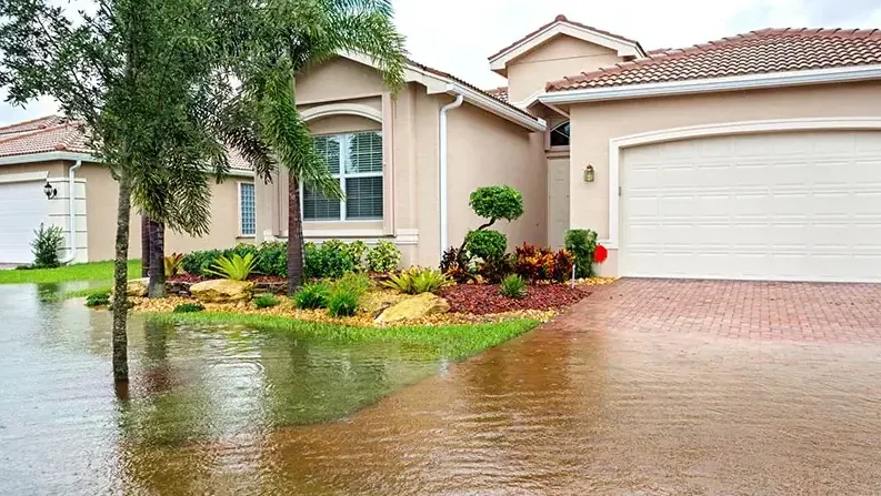 Storm water flooding the front yard and driveway of a stucco home
