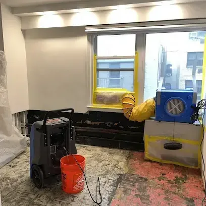 Dehumidifier and air mover running in a room where the flooring has been taken up