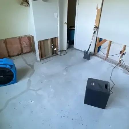 Air movers and a dehumidifier running in a room with the lower drywall removed